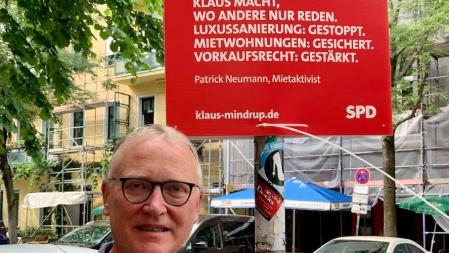 Klaus präsentiert das Wahlplakat mit dem Zitat von Patrick Neumann, Mitaktivist