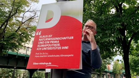 Klaus befestigt das Plakat mit dem Zitat von Prof. Dr. Dr. h.c. Hans Joachim Schellnhuber