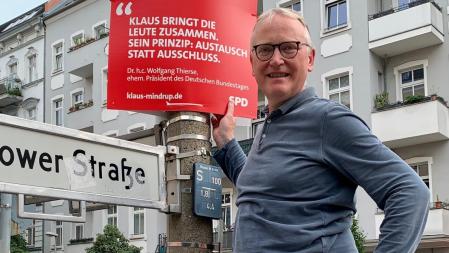 Klaus steht auf einer Leiter und zeigt das Plakat mit dem Zitat von Dr. h.c. Wolfgang Thierse